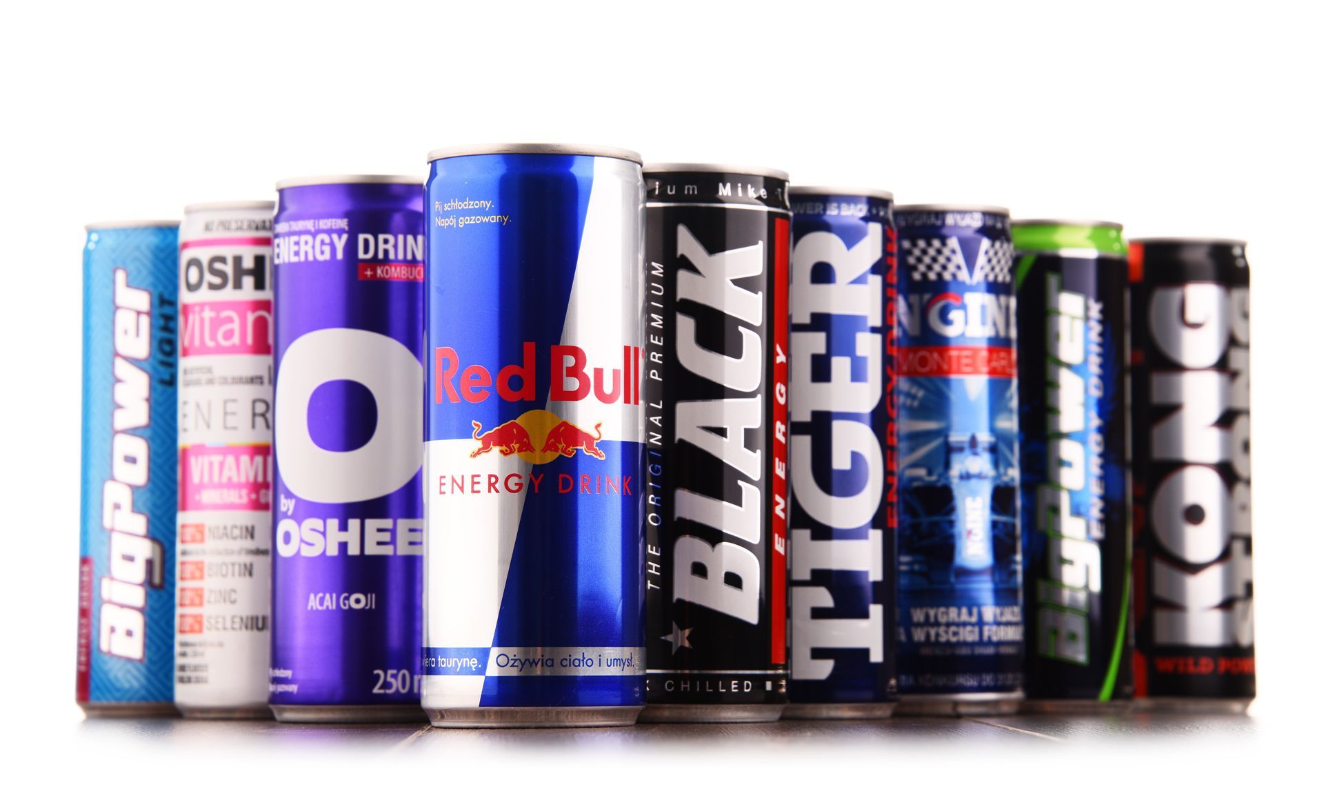Assorted energy drink cans lined up in a row, featuring colorful labels like Red Bull, Black, and Tiger.