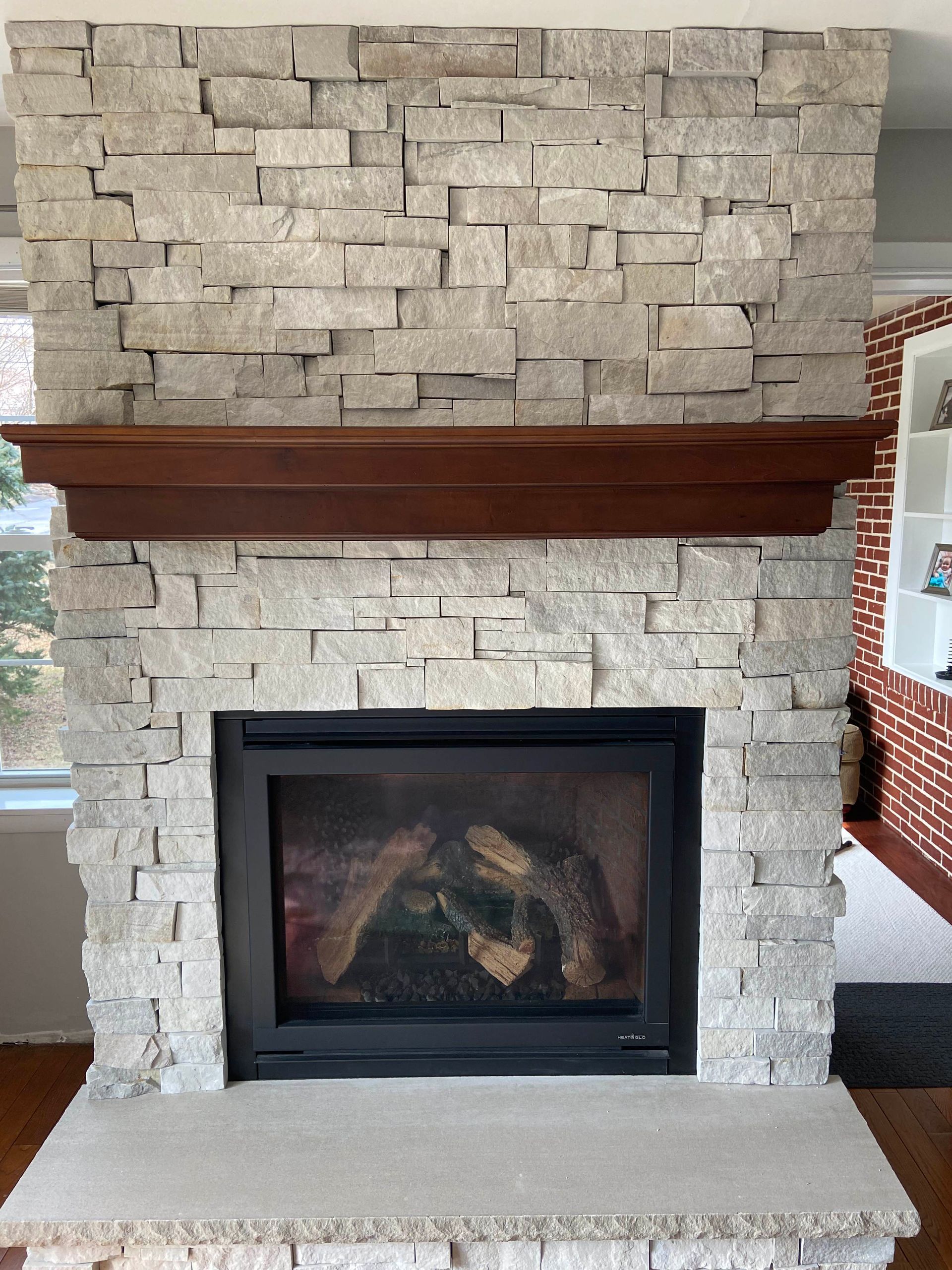 Fireplace with fire, stone facade, decorated with small trees and bear figures.