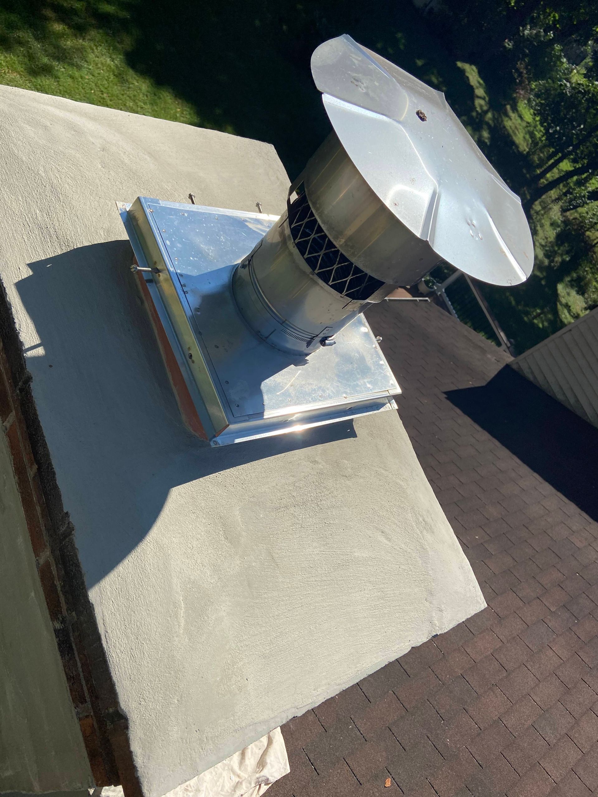 Person on a roof wearing a safety harness, inspecting a brick chimney.