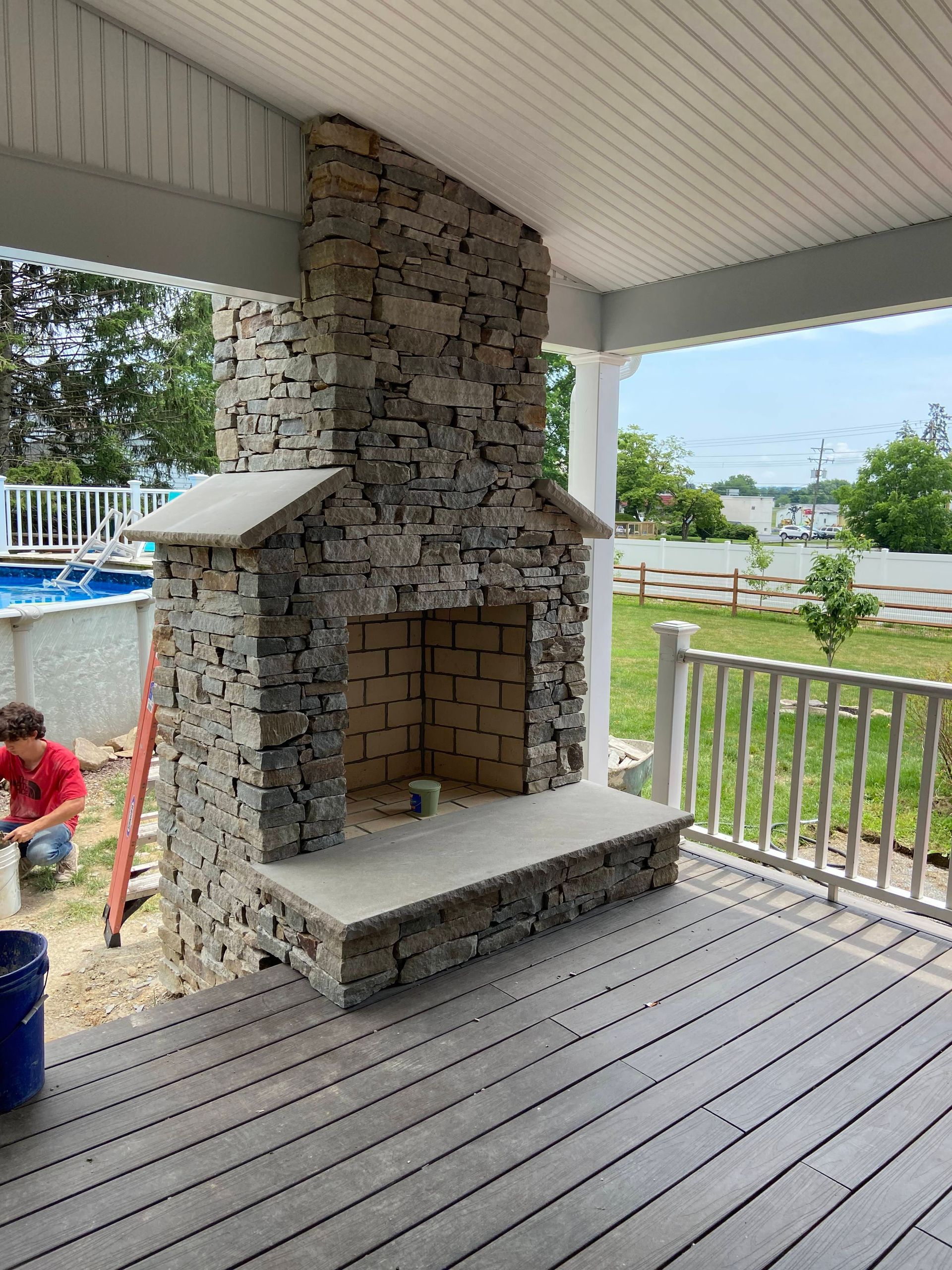 Outdoor stone fireplace with wreath, pumpkins, and mums.