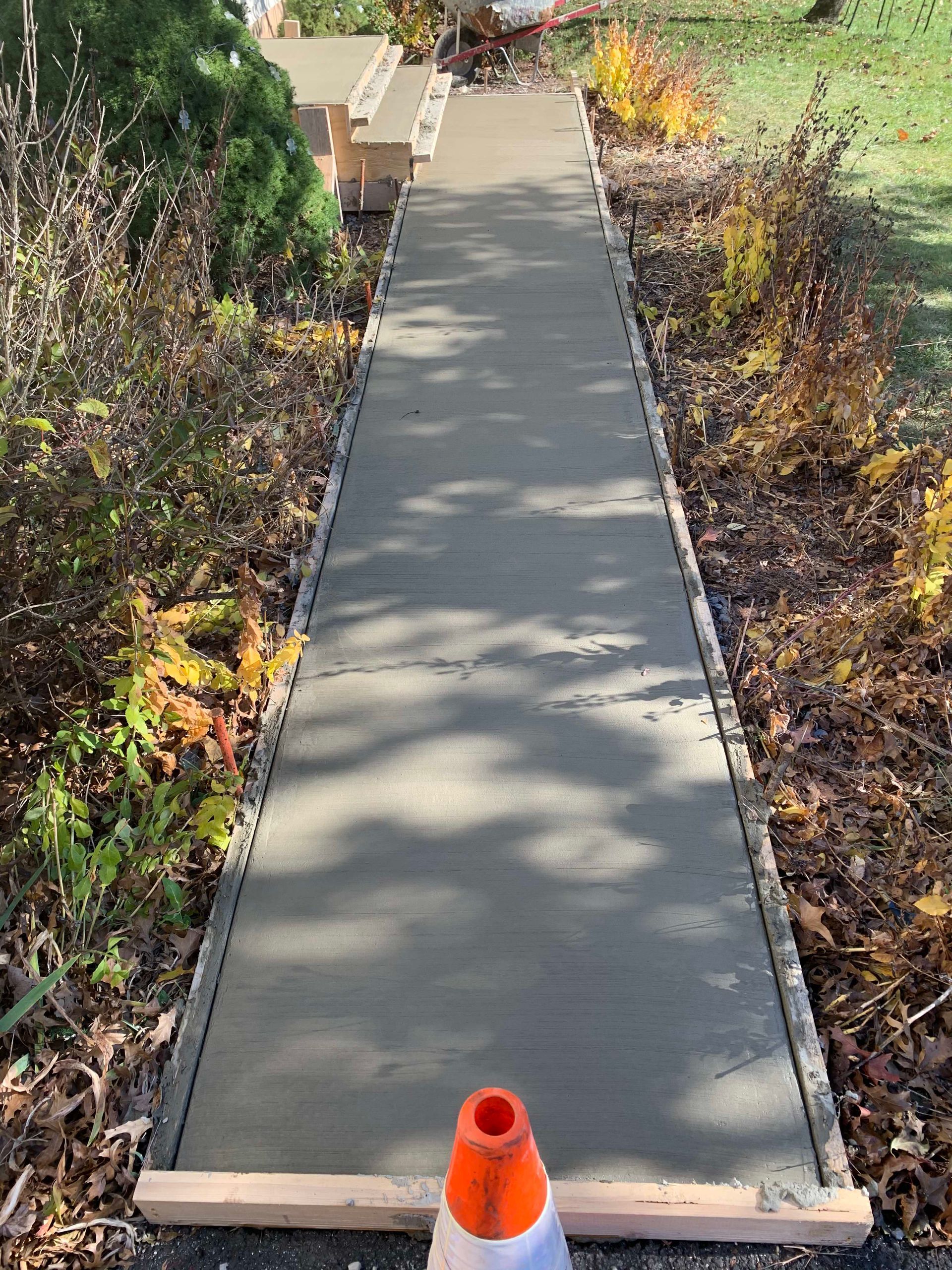 Pathway and steps leading to a white colonial house on a sunny day.