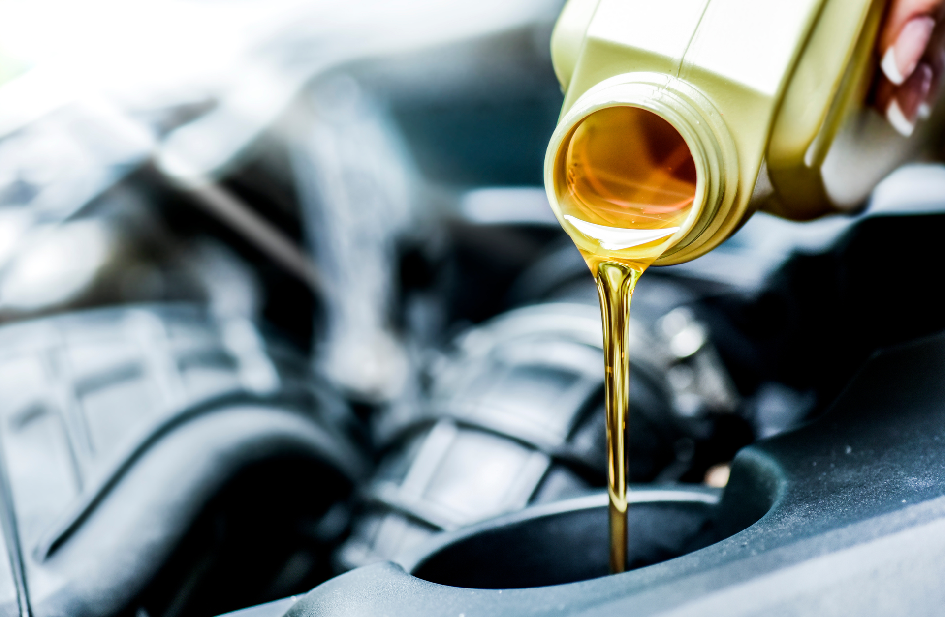 A person is pouring oil into a car engine.