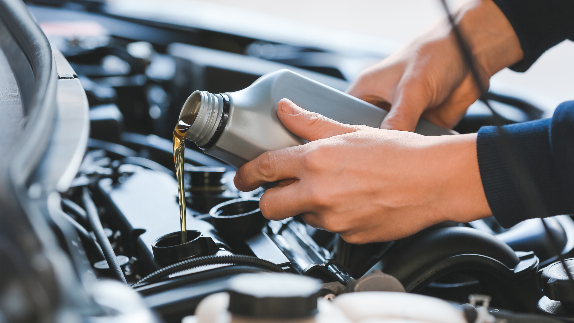 A person is pouring oil into a car engine.