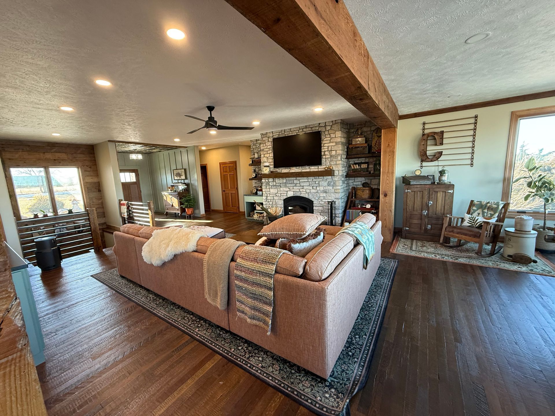 Rustic kitchen with weathered wood walls, corrugated metal ceiling, concrete floor, stainless steel refrigerator.