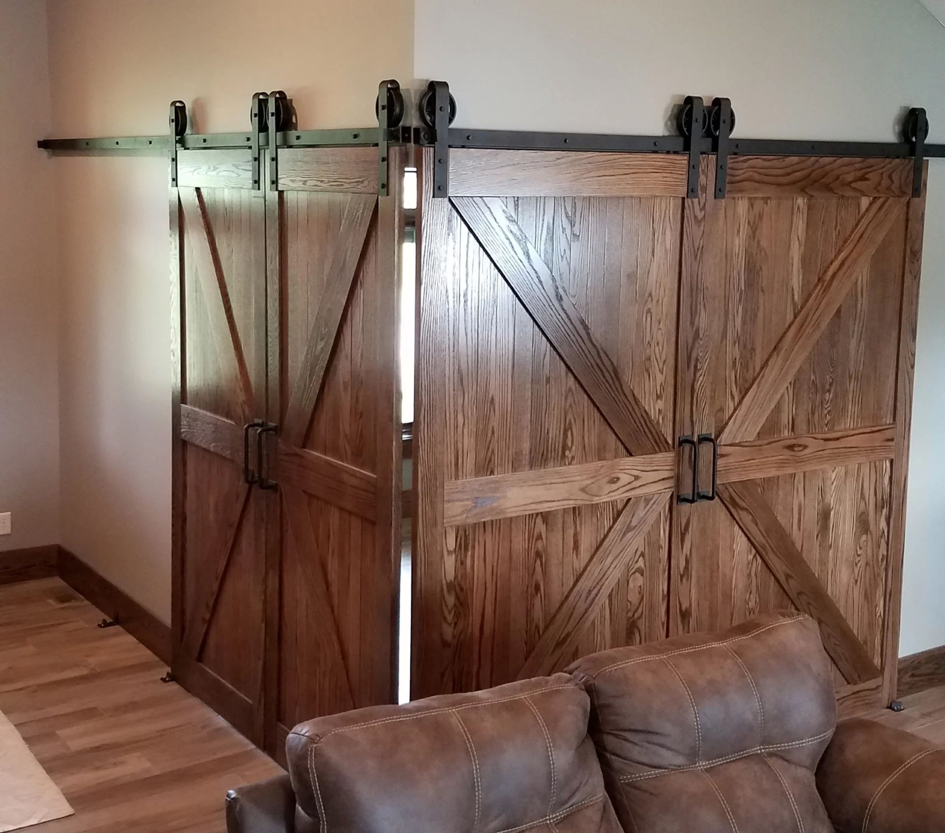 Two wooden barn doors with black hardware, partially open, against a tan wall.