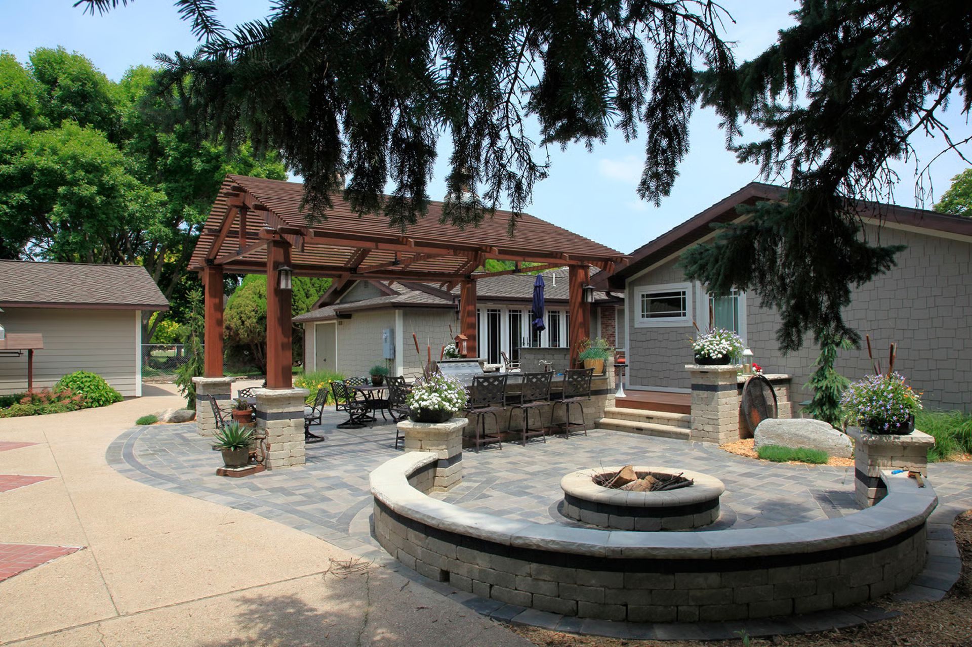 Backyard patio with fire pit, seating, pergola, and two-tone brickwork.