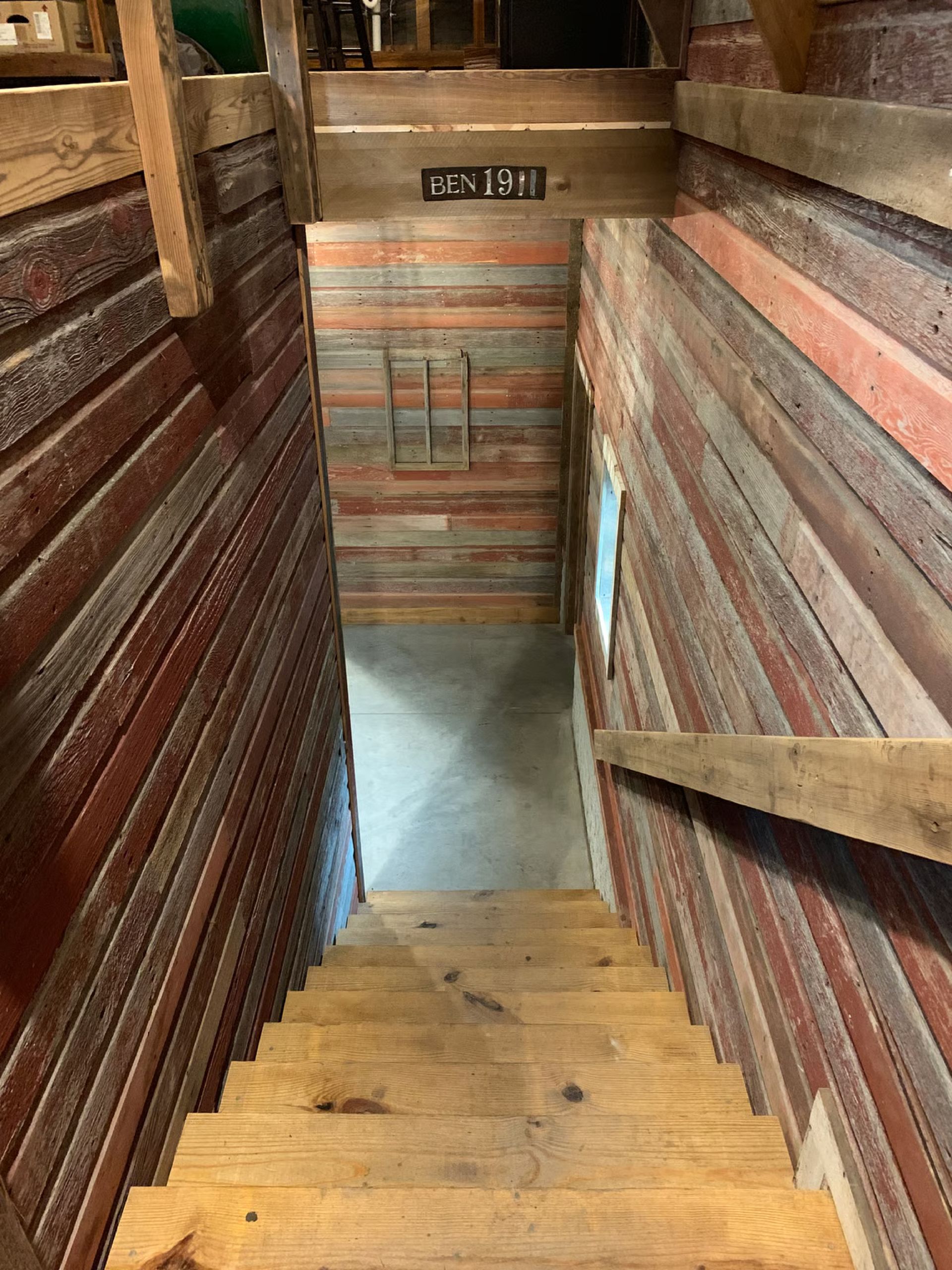 Wooden staircase leading down into a long, narrow room with wood-paneled walls.