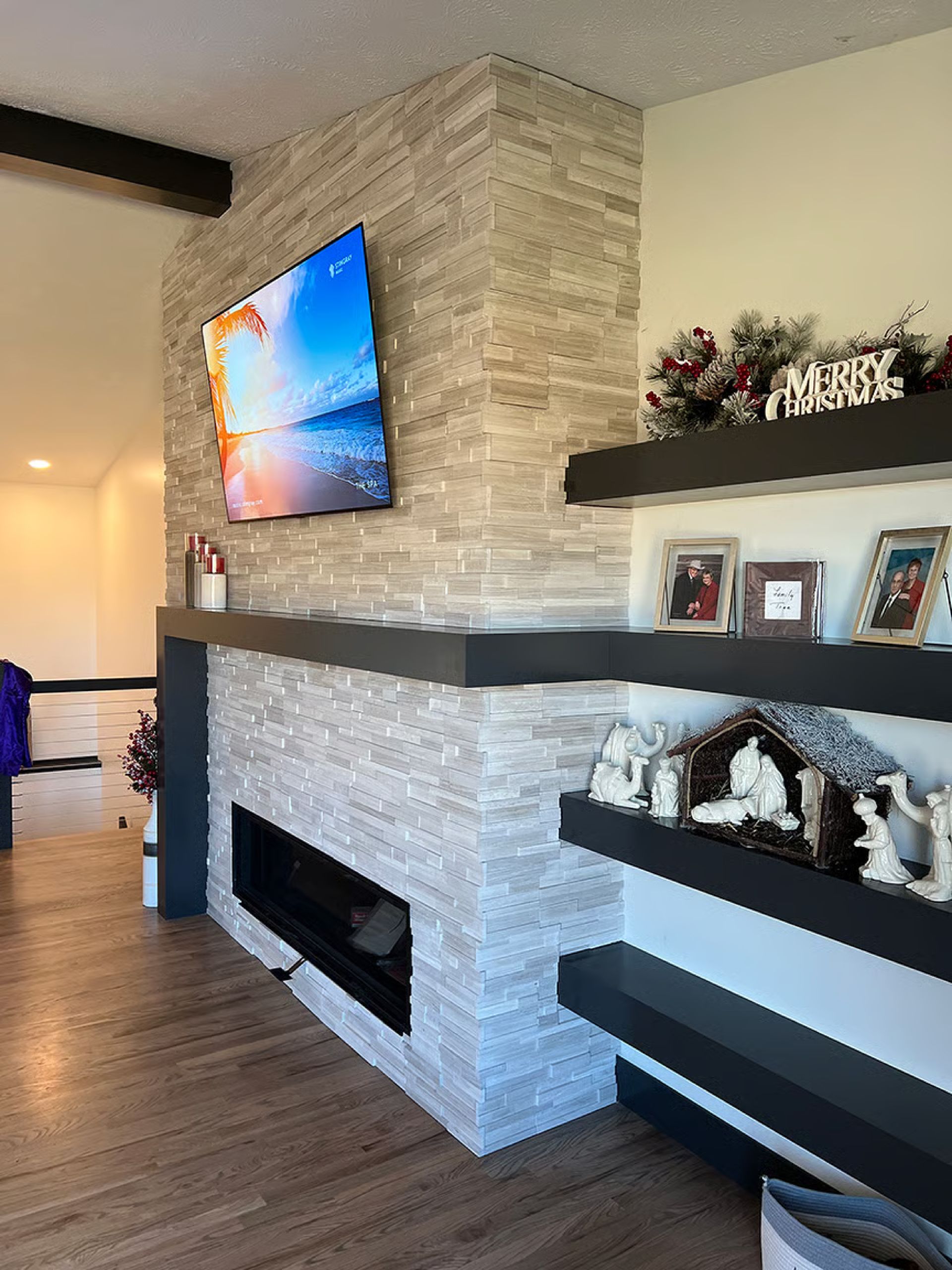 Stone fireplace with a TV, shelves, and Christmas decorations.