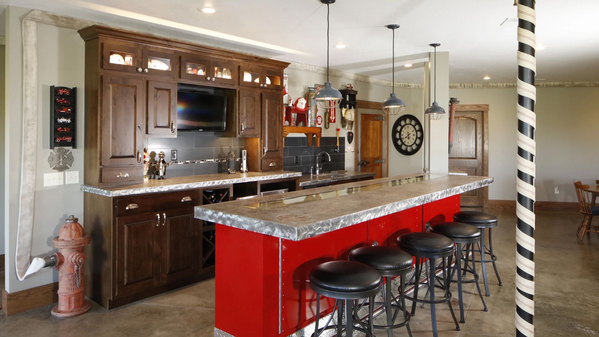 A red and brown home bar with stools, a granite countertop, cabinets, and a fire hydrant.