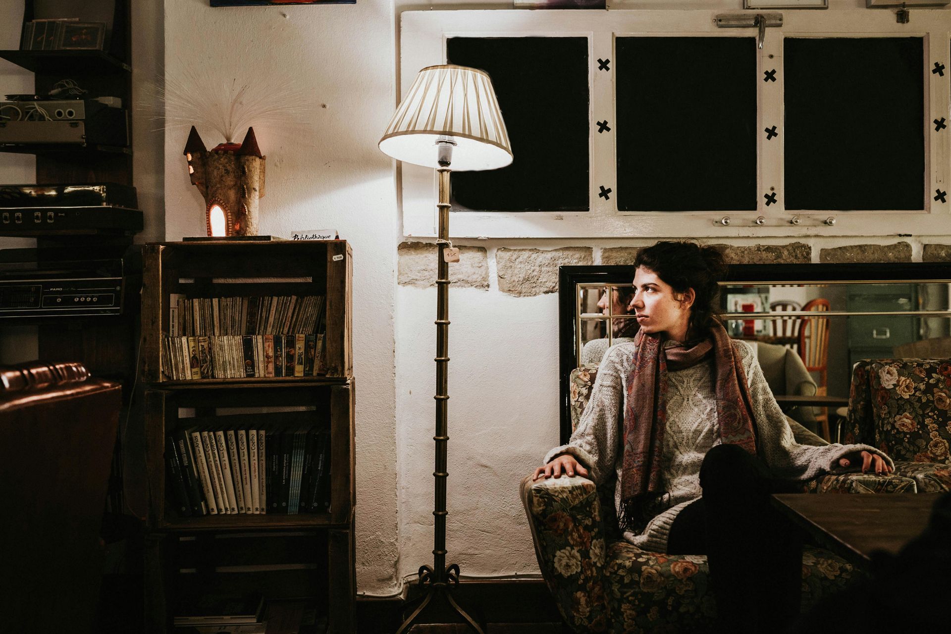 A woman sits thoughtfully in a cozy, softly lit, basement living area, illustrating the comfort and 