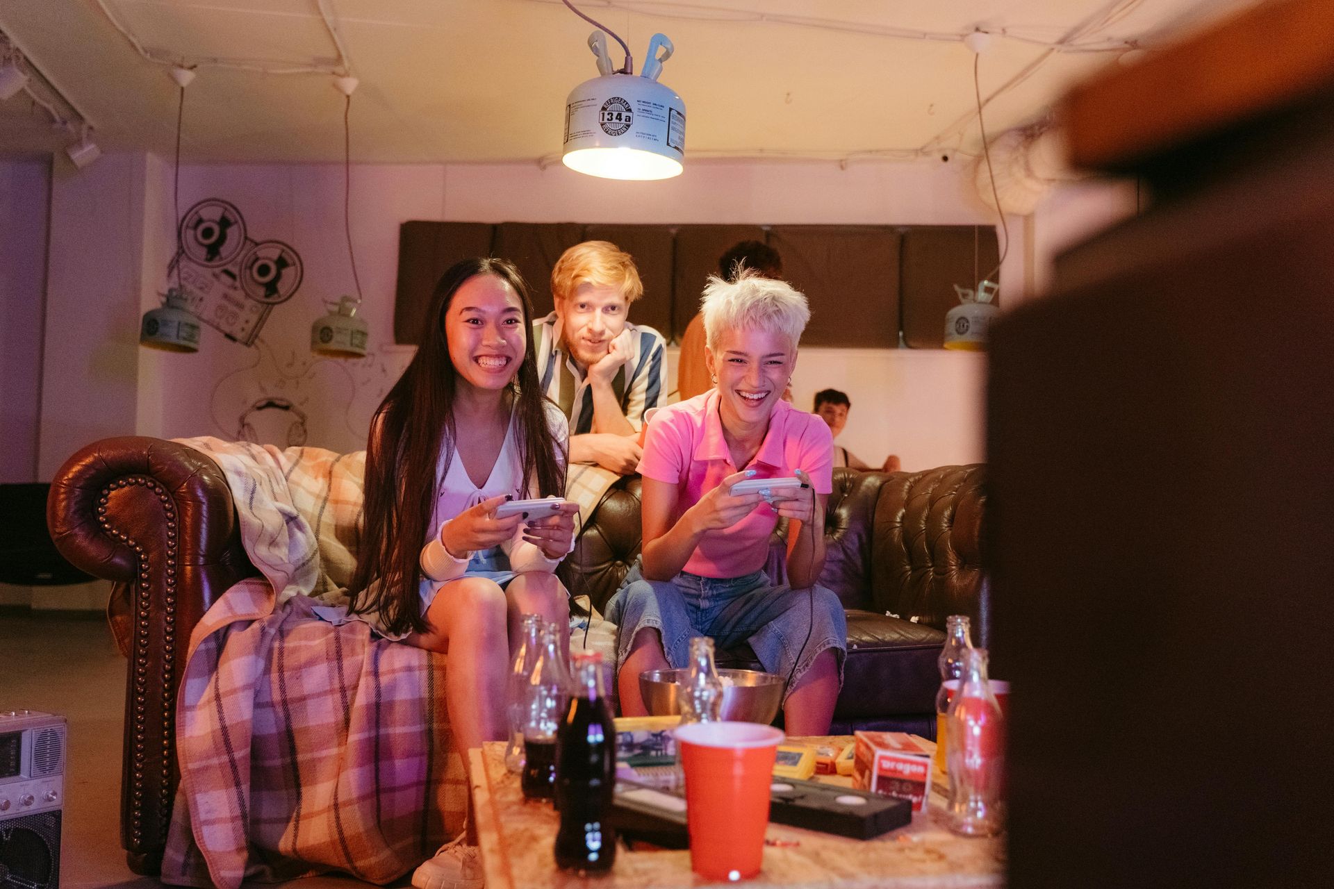 A group of friends plays video games on a couch in a stylish remodeled basement.
