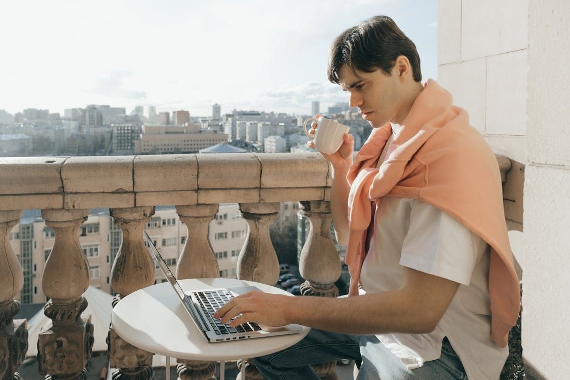 Man using a computer while drinking coffee.