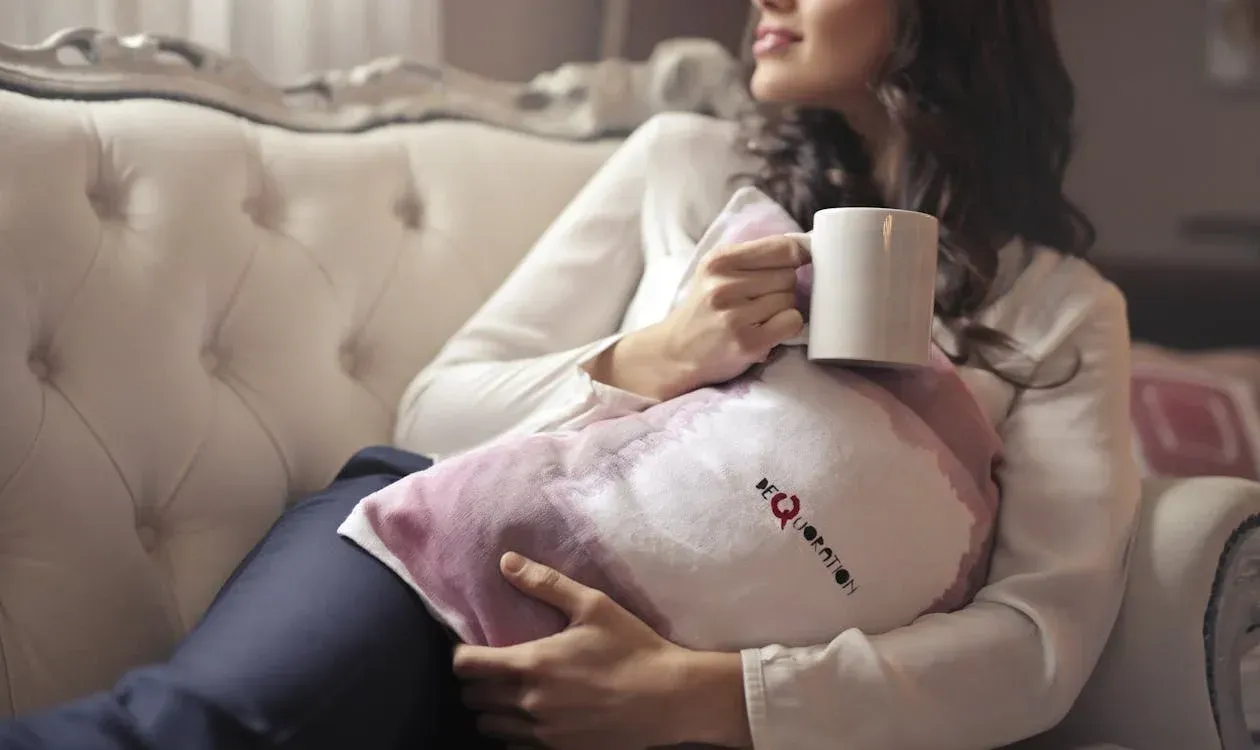 A woman drinking coffee while on the couch