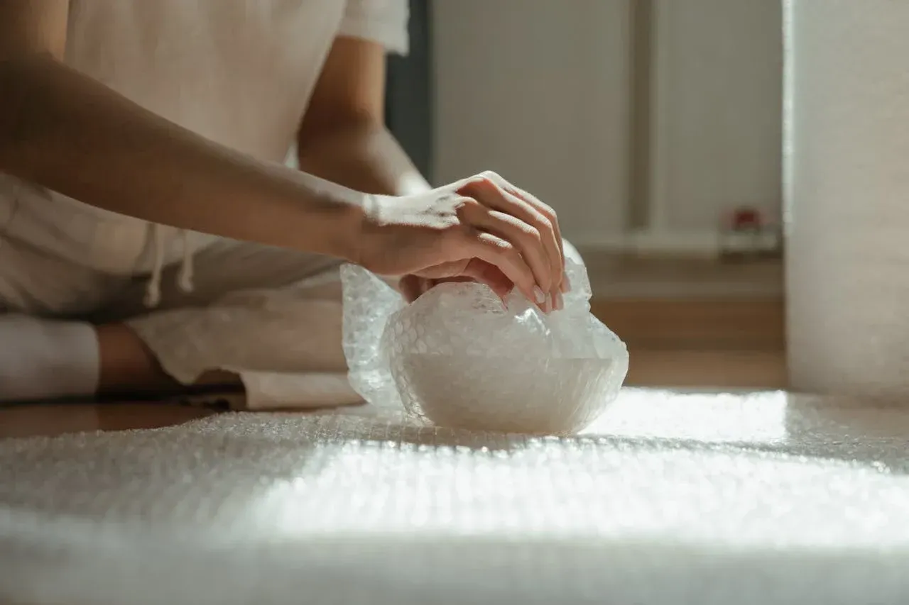 Woman packing a bowl in bubble wrap
