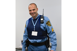 A man in a blue uniform is holding a walkie talkie.