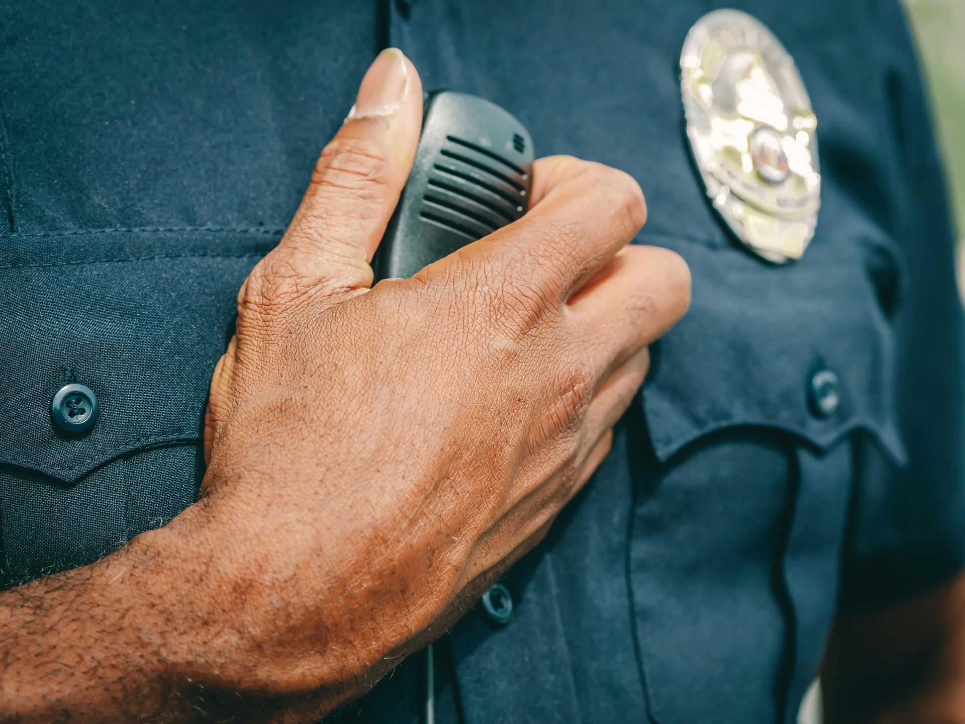 A police officer is holding a walkie talkie in his pocket.