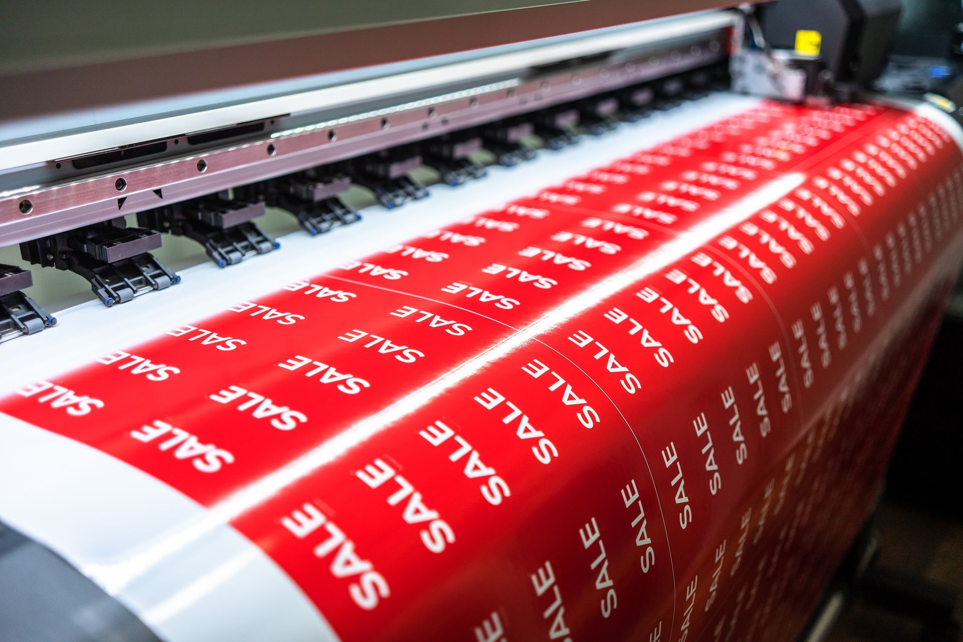 Large format printer producing red sale banners in a commercial printing facility.