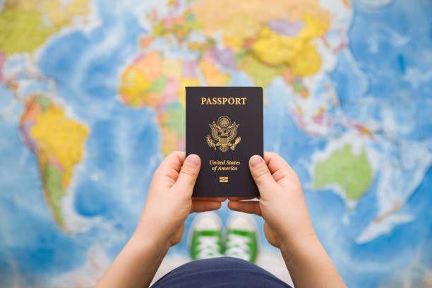 A person is holding a passport in front of a map of the world. - Port Saint John, FL - Shipping Depot of Port St John