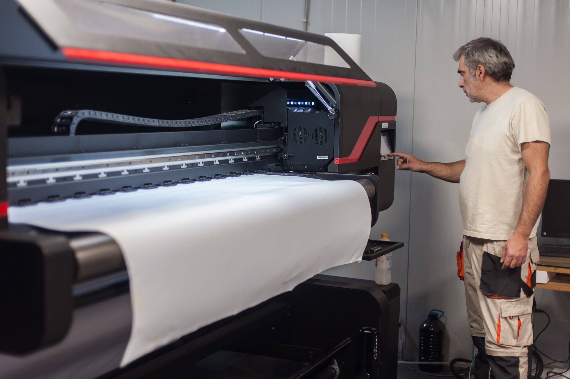 A man is standing in front of a large printer. - Port Saint John, FL - Shipping Depot of Port St John