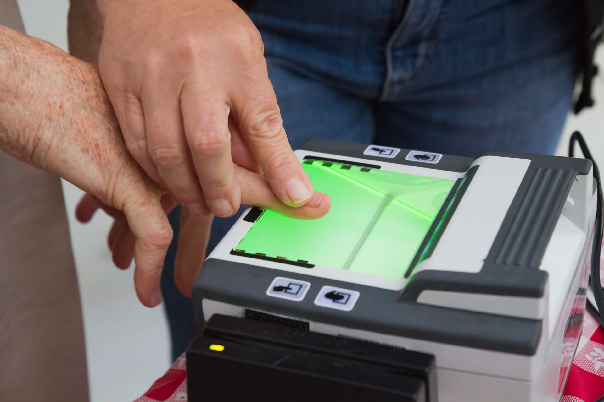 A person is using a machine to scan their fingerprints. - Port Saint John, FL - Shipping Depot of Port St John