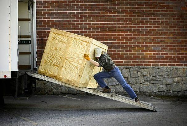 A man is pushing a large wooden box up a ramp. - Port Saint John, FL - Shipping Depot of Port St John