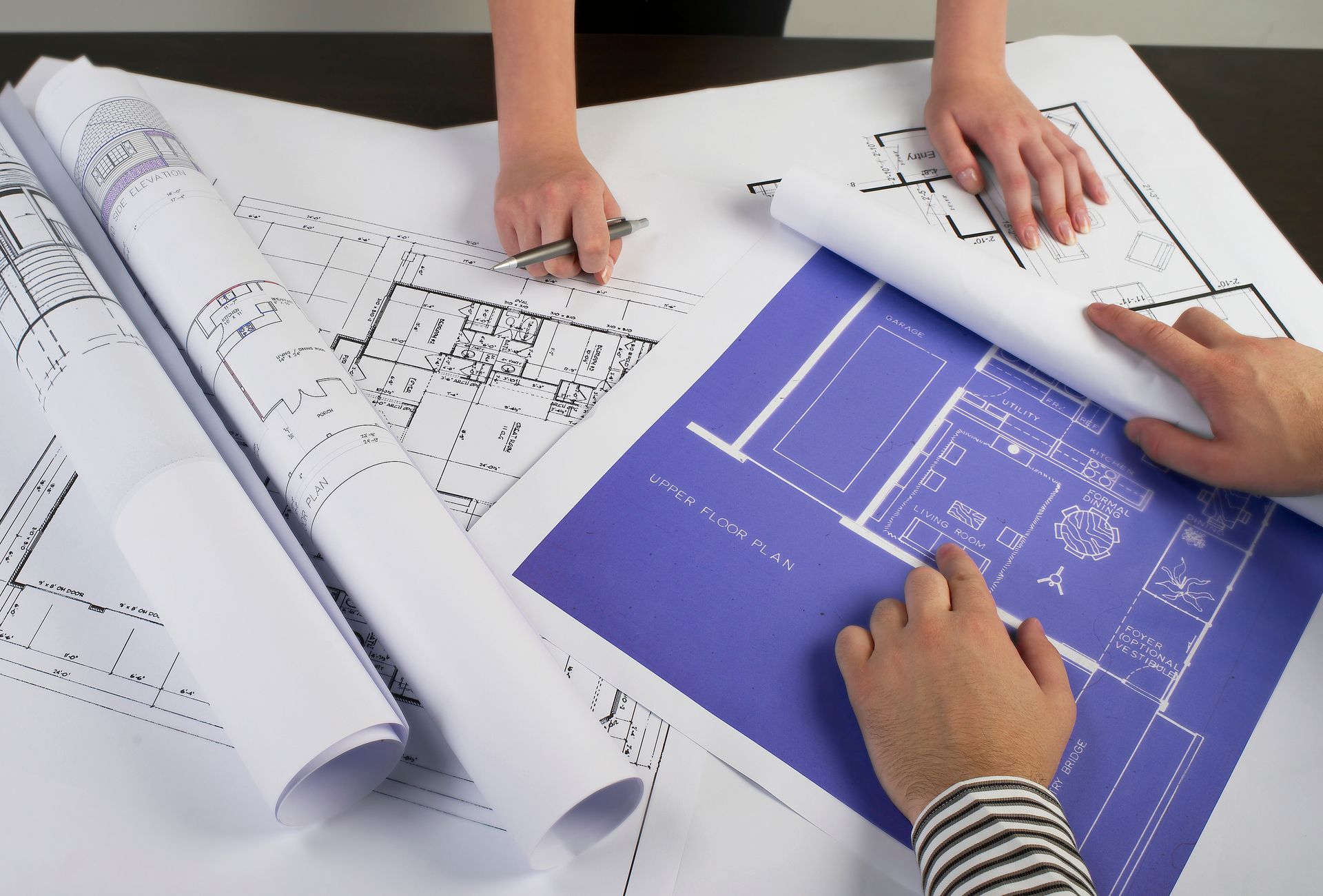 Two people are looking at blueprints on a table. - Port Saint John, FL - Shipping Depot of Port St John