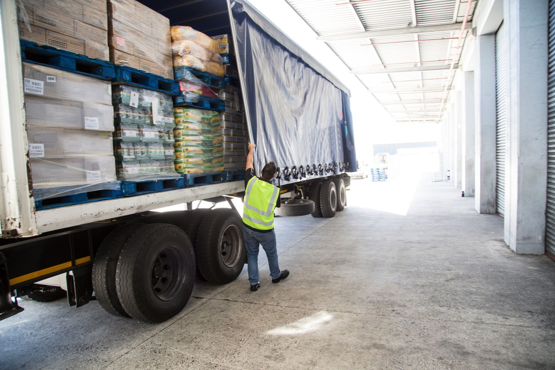 A man is loading a semi-truck in a warehouse. - Port Saint John, FL - Shipping Depot of Port St John
