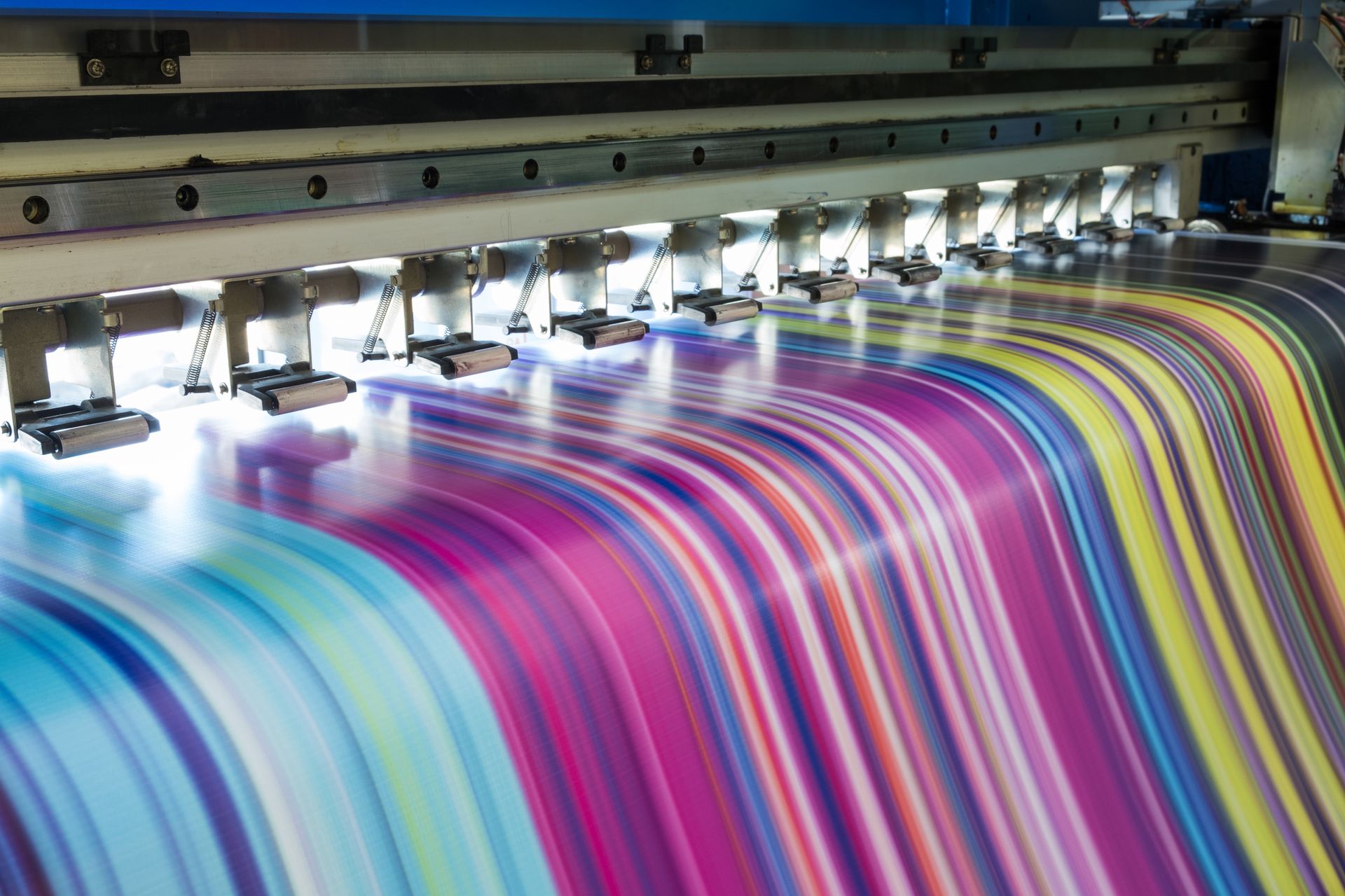 A large printer is printing a colorful striped piece of paper. - Port Saint John, FL - Shipping Depot of Port St John