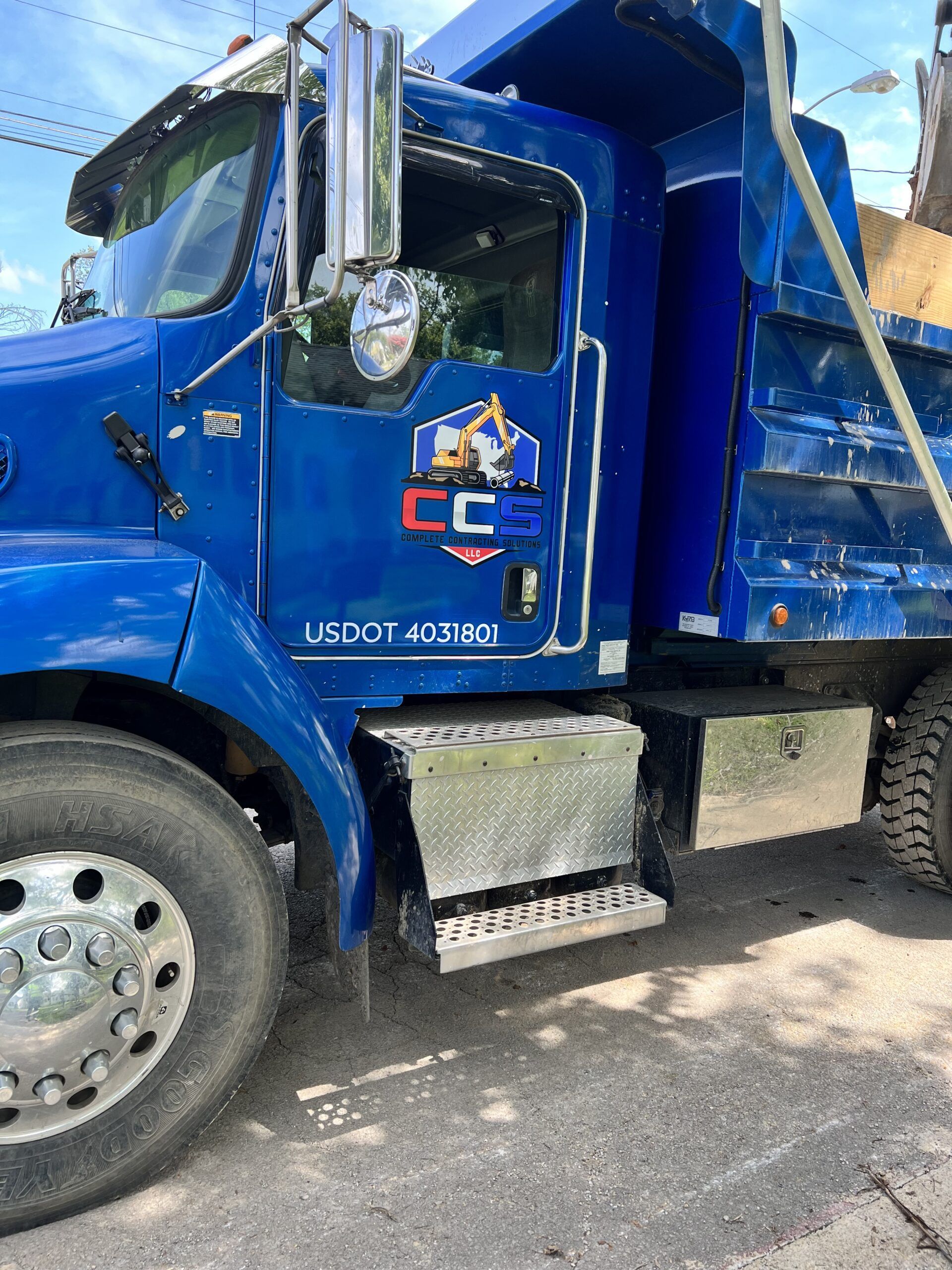 A blue dump truck is parked on the side of the road.