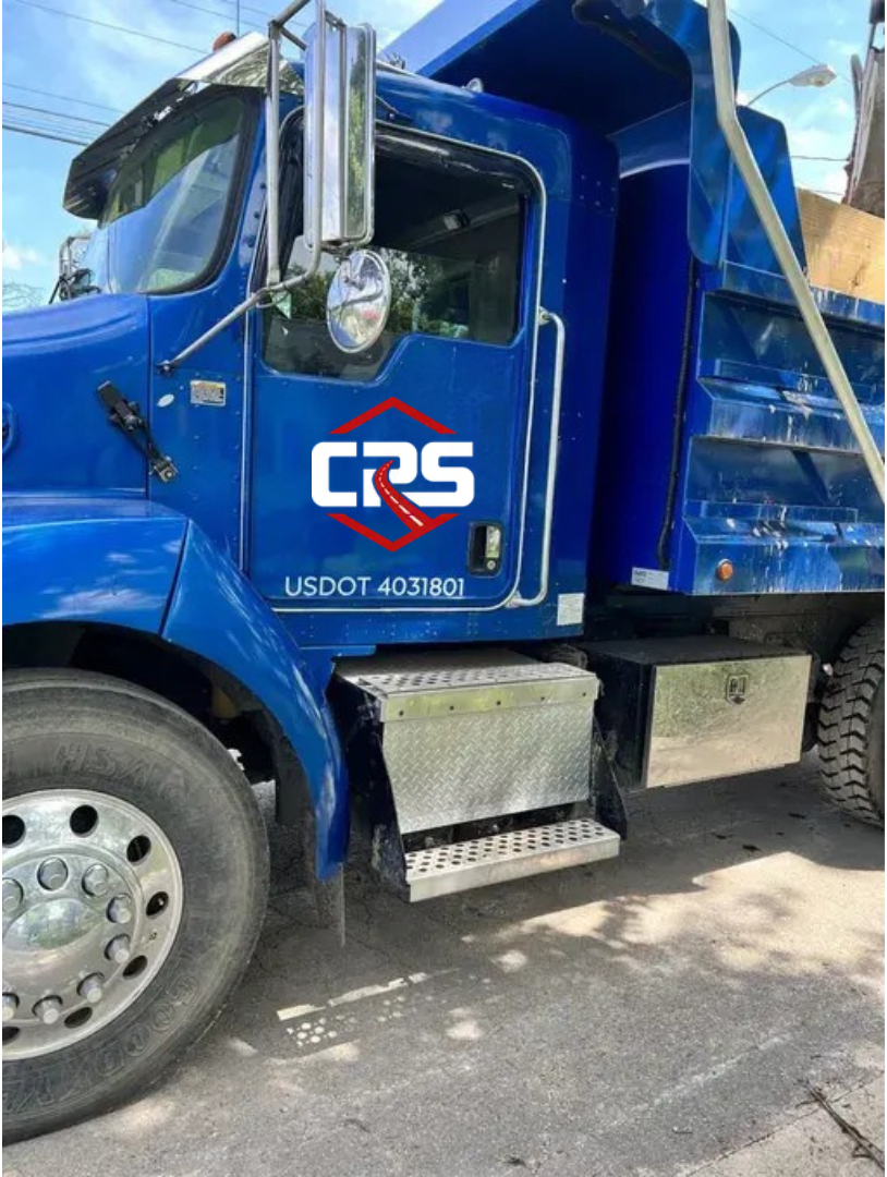 A blue dump truck is parked on the side of the road.