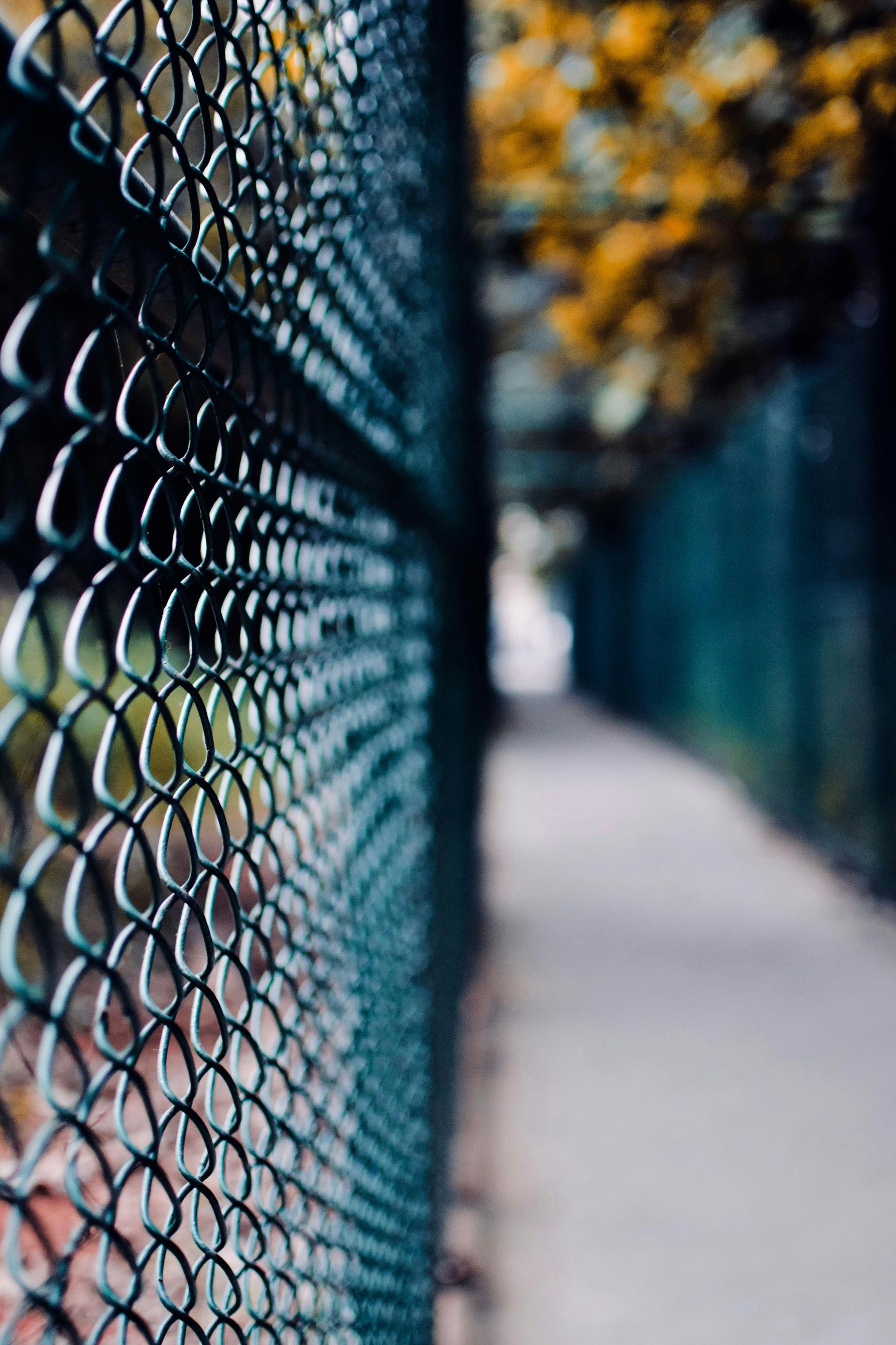A close up of a chain link fence along a sidewalk.