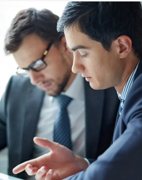 Two men in suits and ties are looking at a tablet