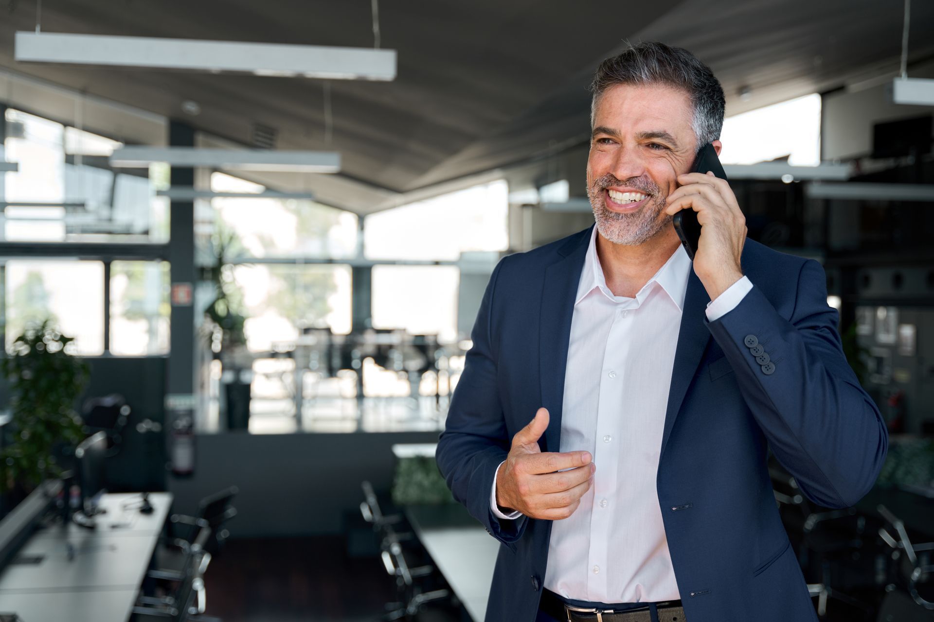 A man in a suit is talking on a cell phone in an office.