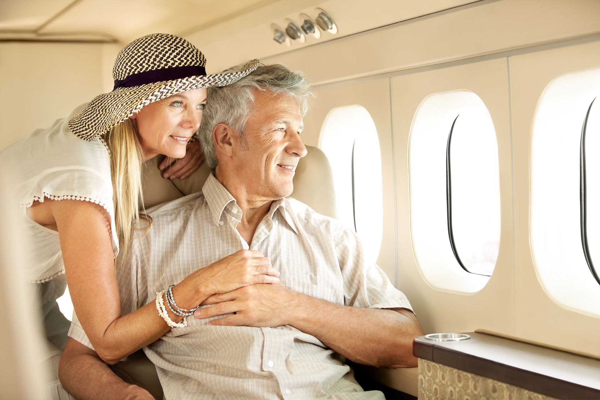A woman is hugging an older man on an airplane.