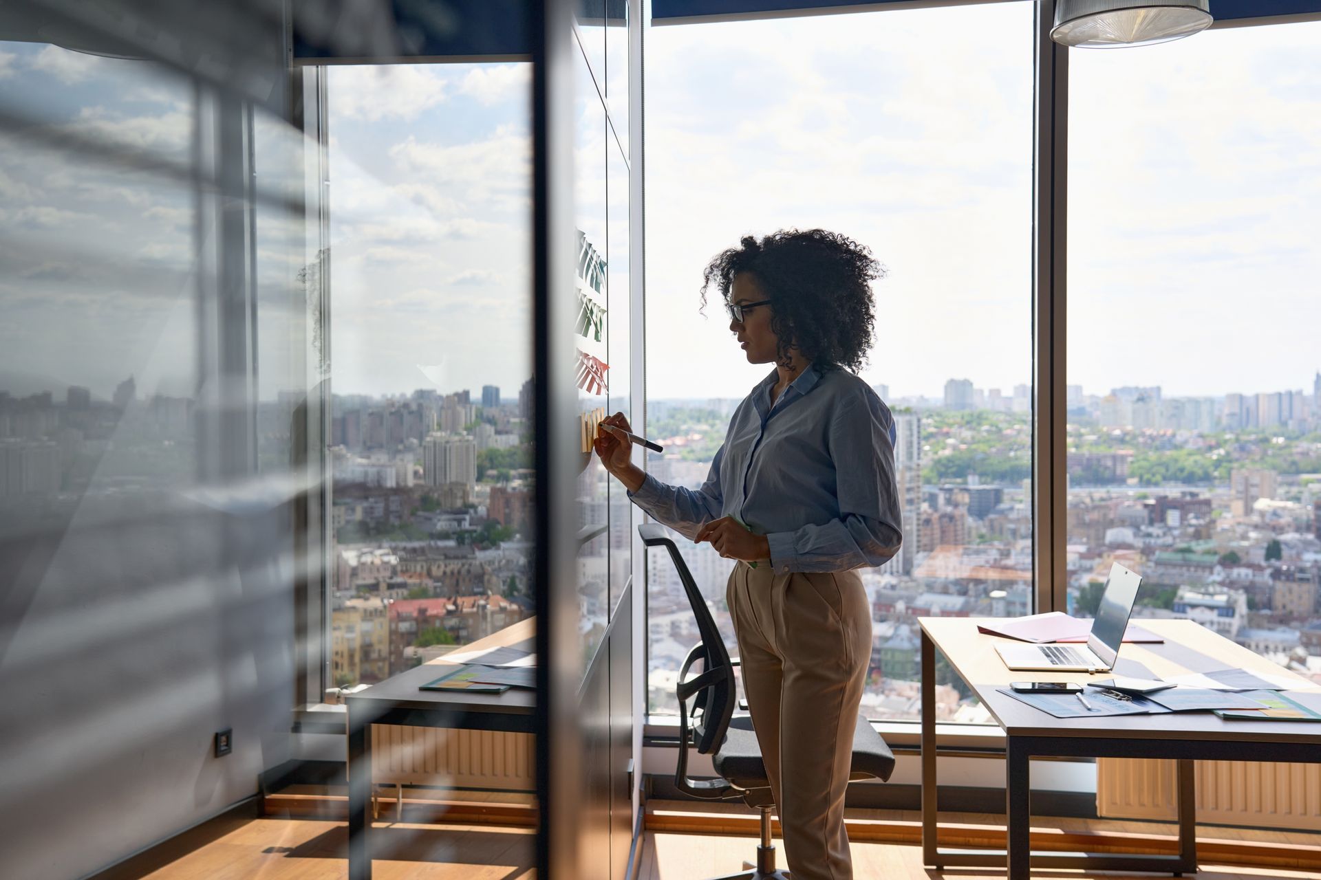 A woman is writing on a whiteboard in an office.