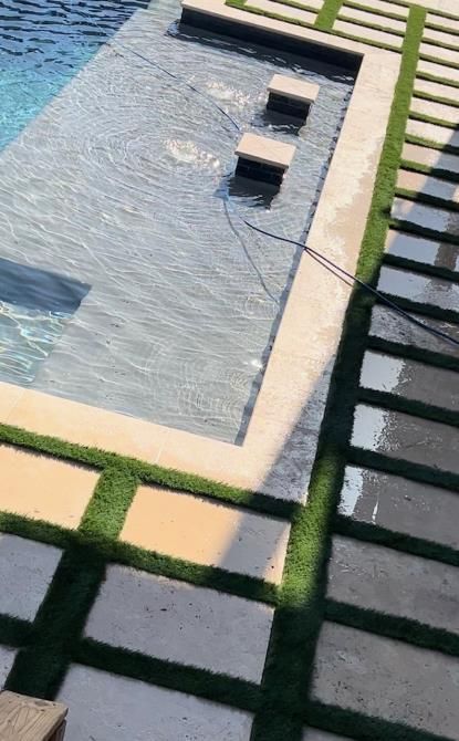 A large swimming pool surrounded by steps and grass.