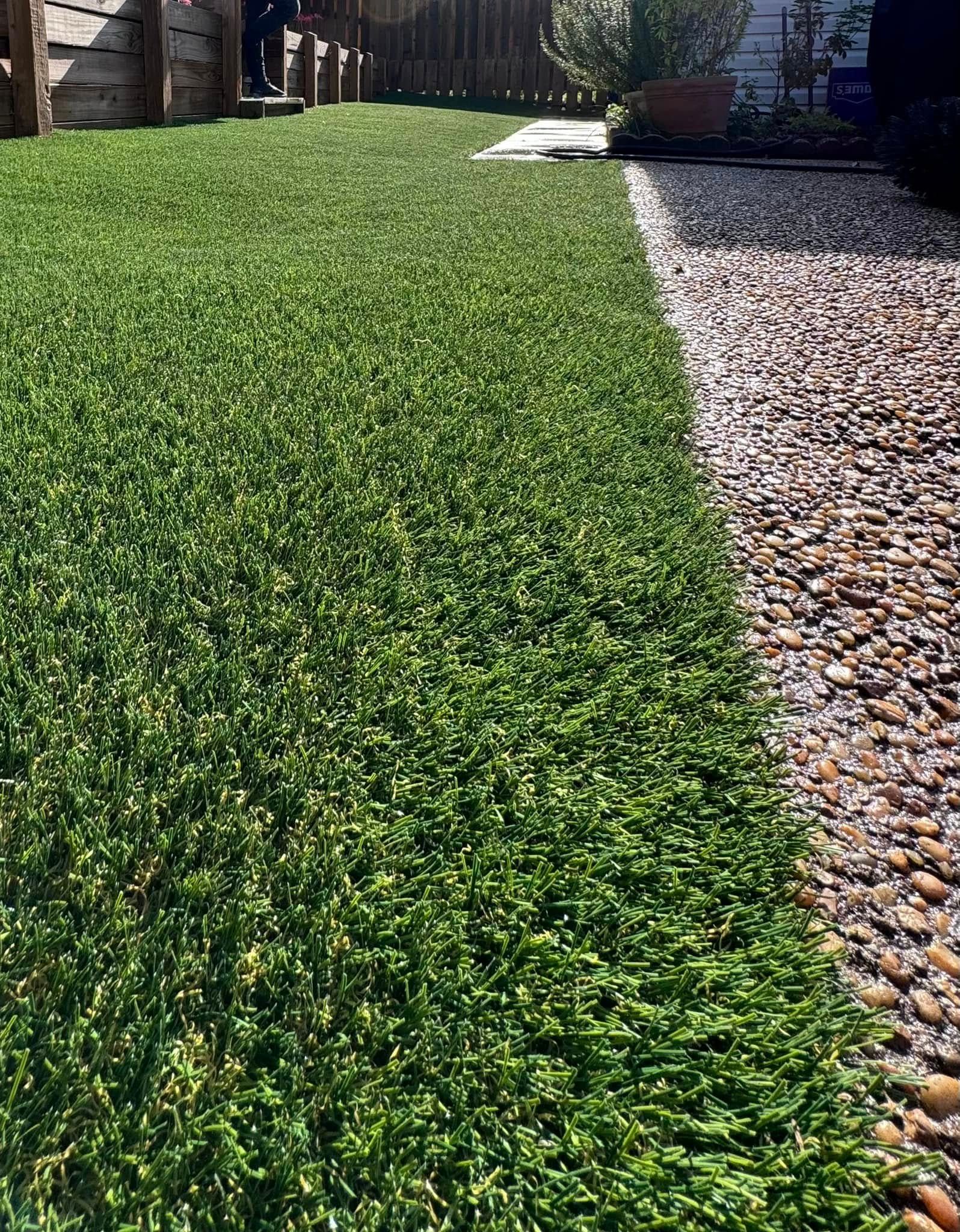 A close up of a lush green lawn next to a gravel path.
