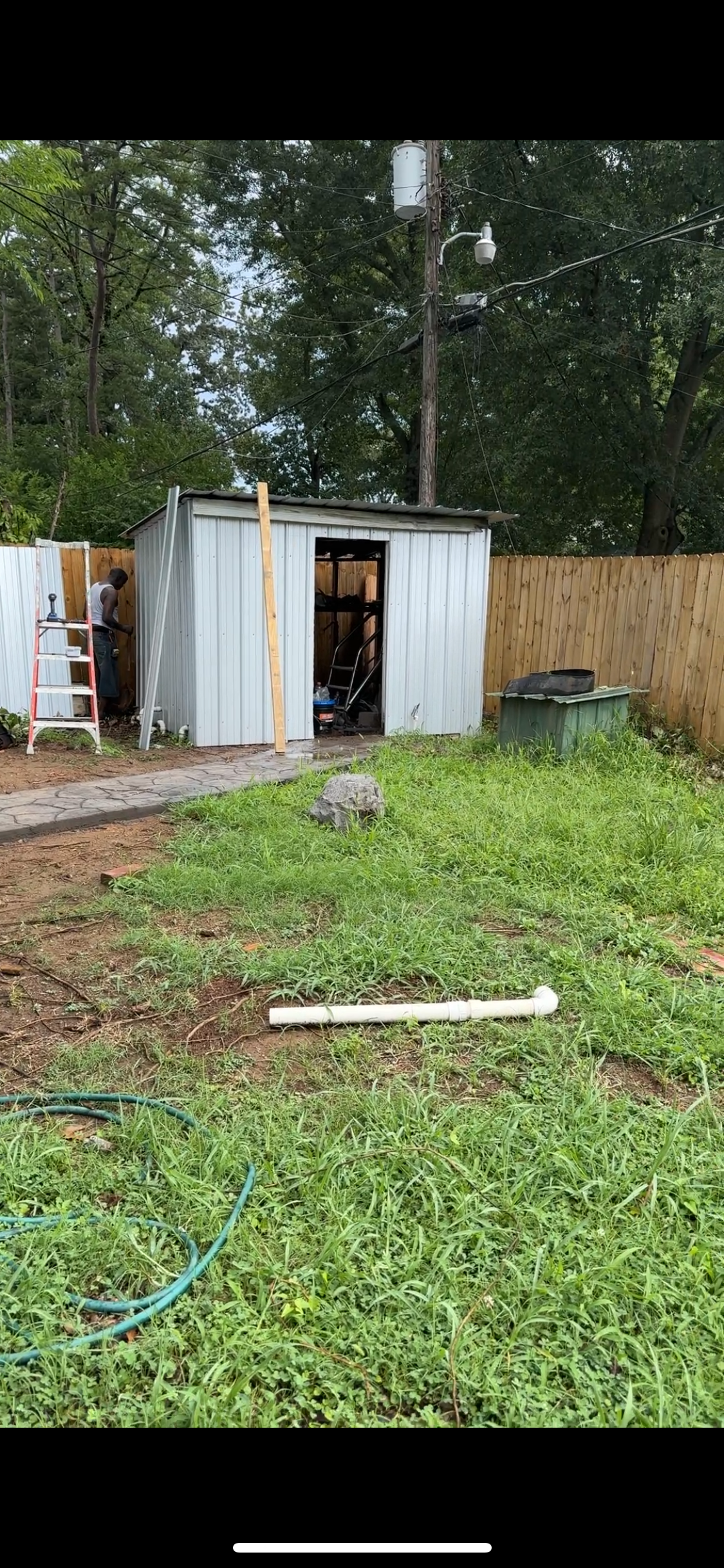 A shed is sitting in the middle of a grassy field.