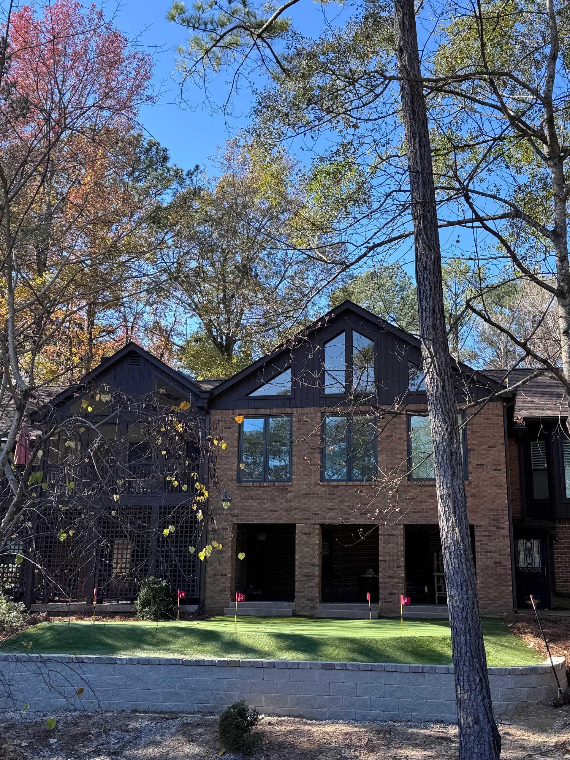A large brick house is surrounded by trees on a sunny day.