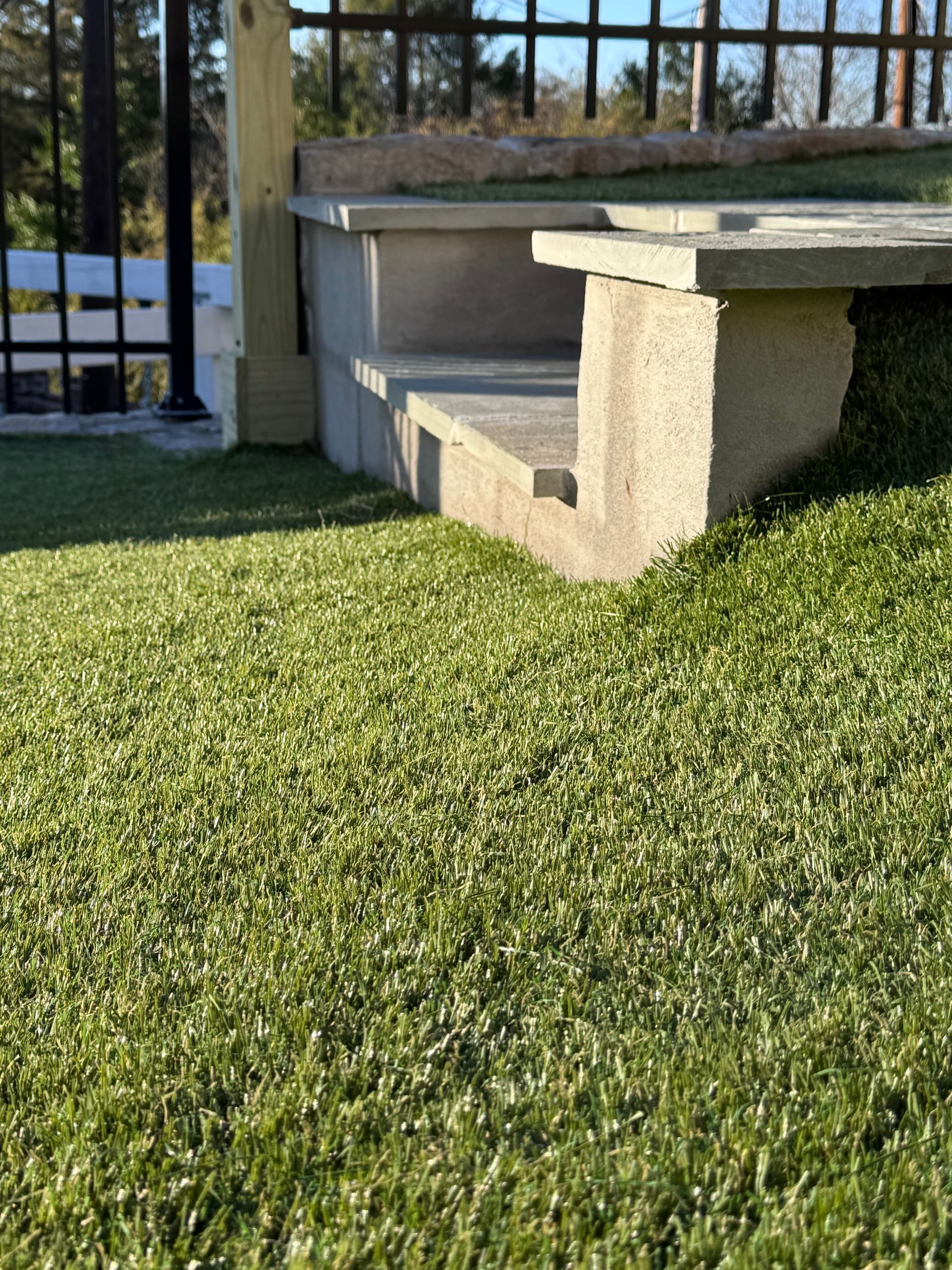 A concrete bench is sitting on top of a lush green lawn.