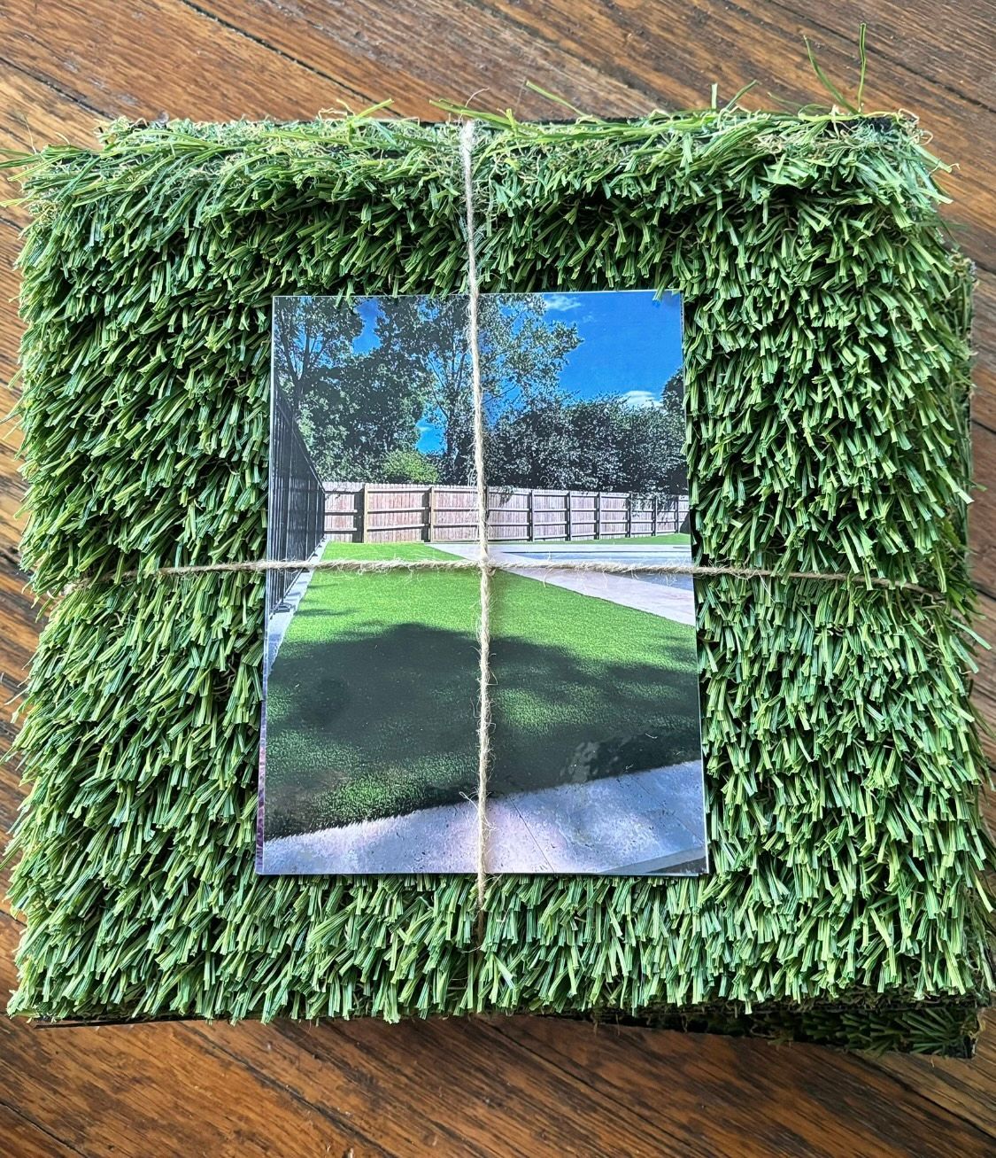A picture of a lawn in a picture frame on a wooden table.