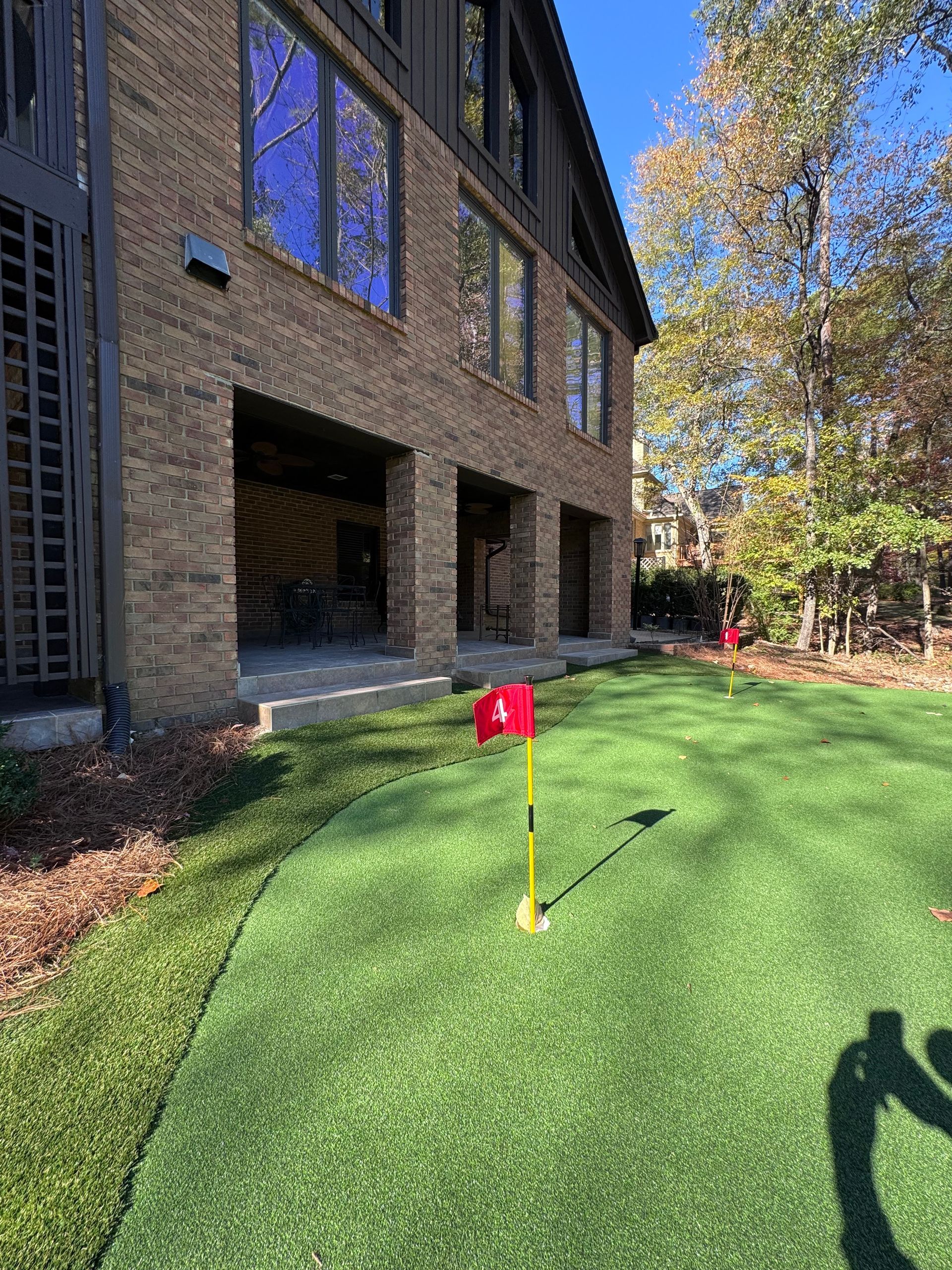 A putting green in front of a large brick building.