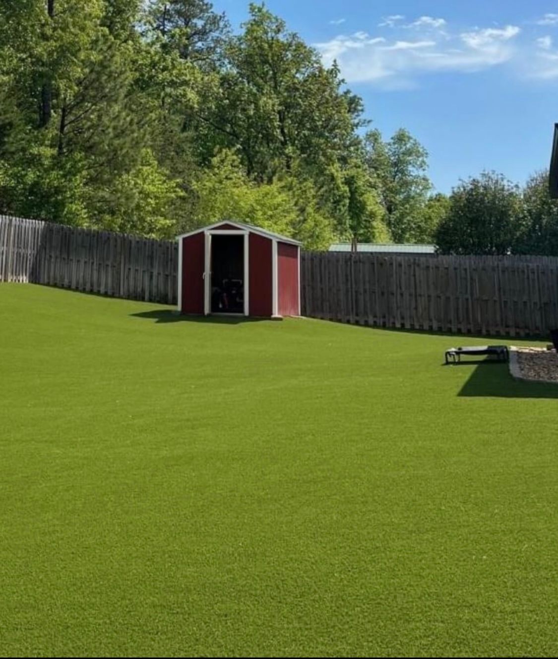 A red shed sits in the middle of a lush green yard