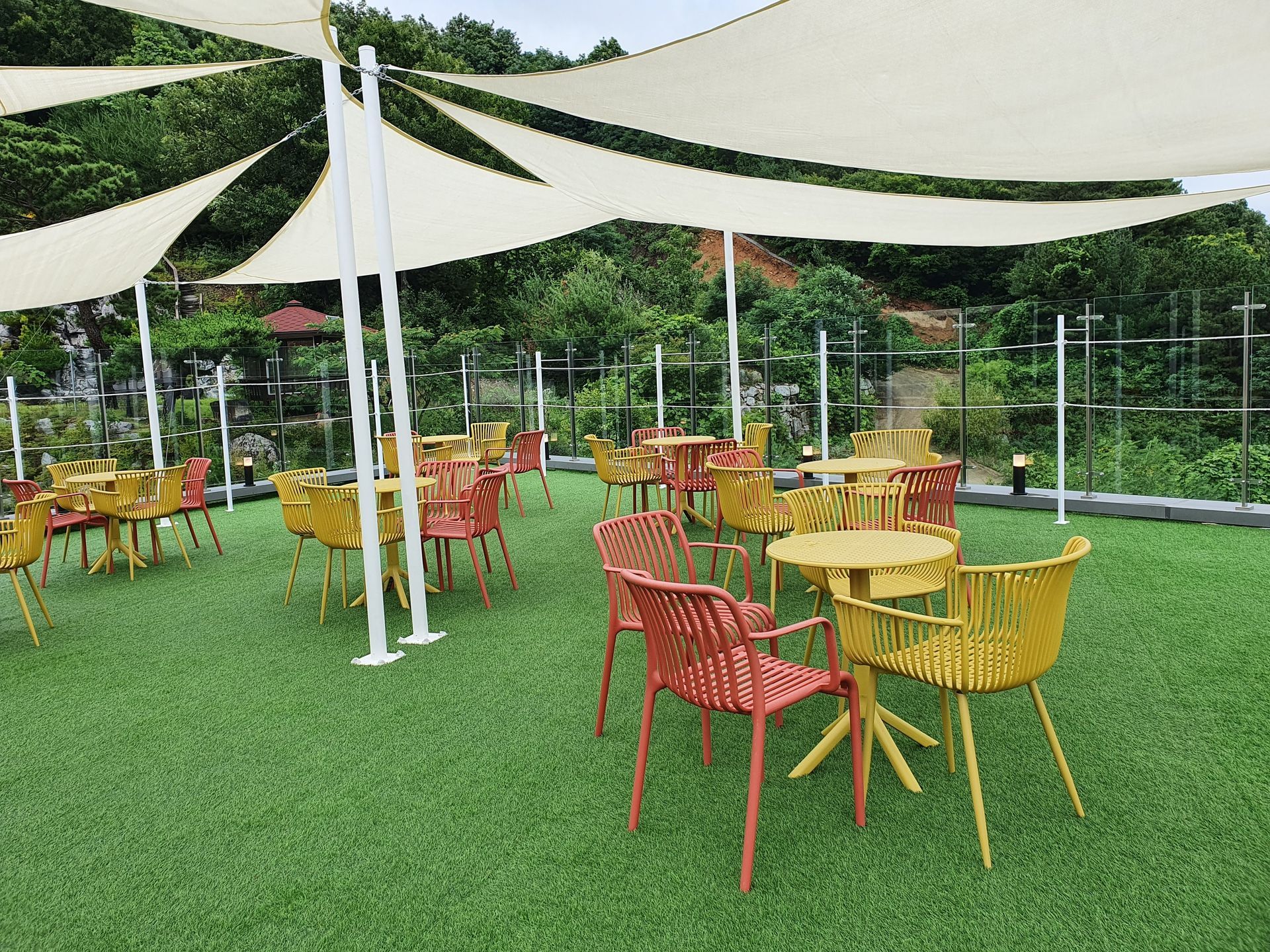 A lawn with tables and chairs under umbrellas.