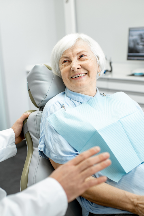 Old woman smiling in dental chair | Get full dentures and a complete smile makeover | Dentist near Houston 77042