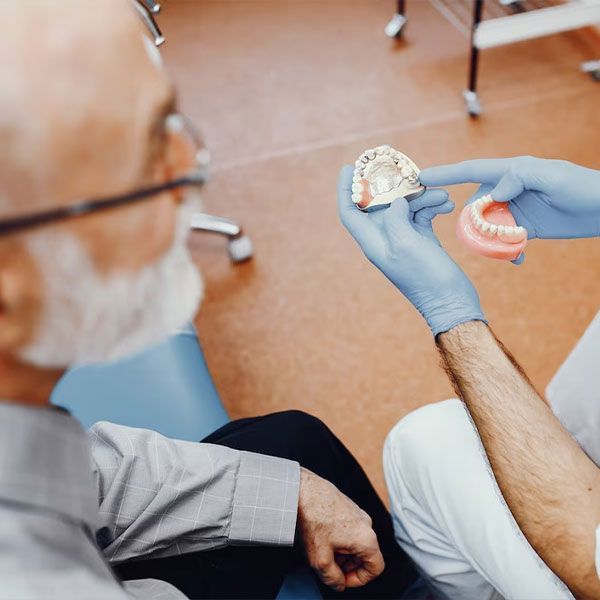 dentist showing denture samples | Best Full and Partial Dentures | Houston TX 77042