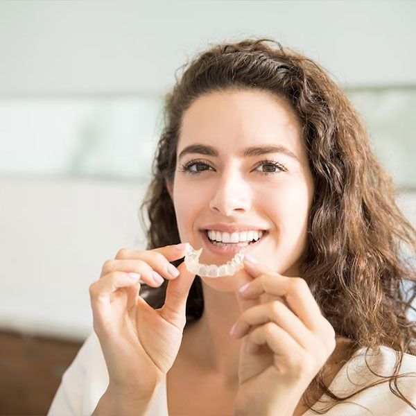 female patient holding invisalign | Get a straighter smile with discreet Invisalign Clear Aligners.