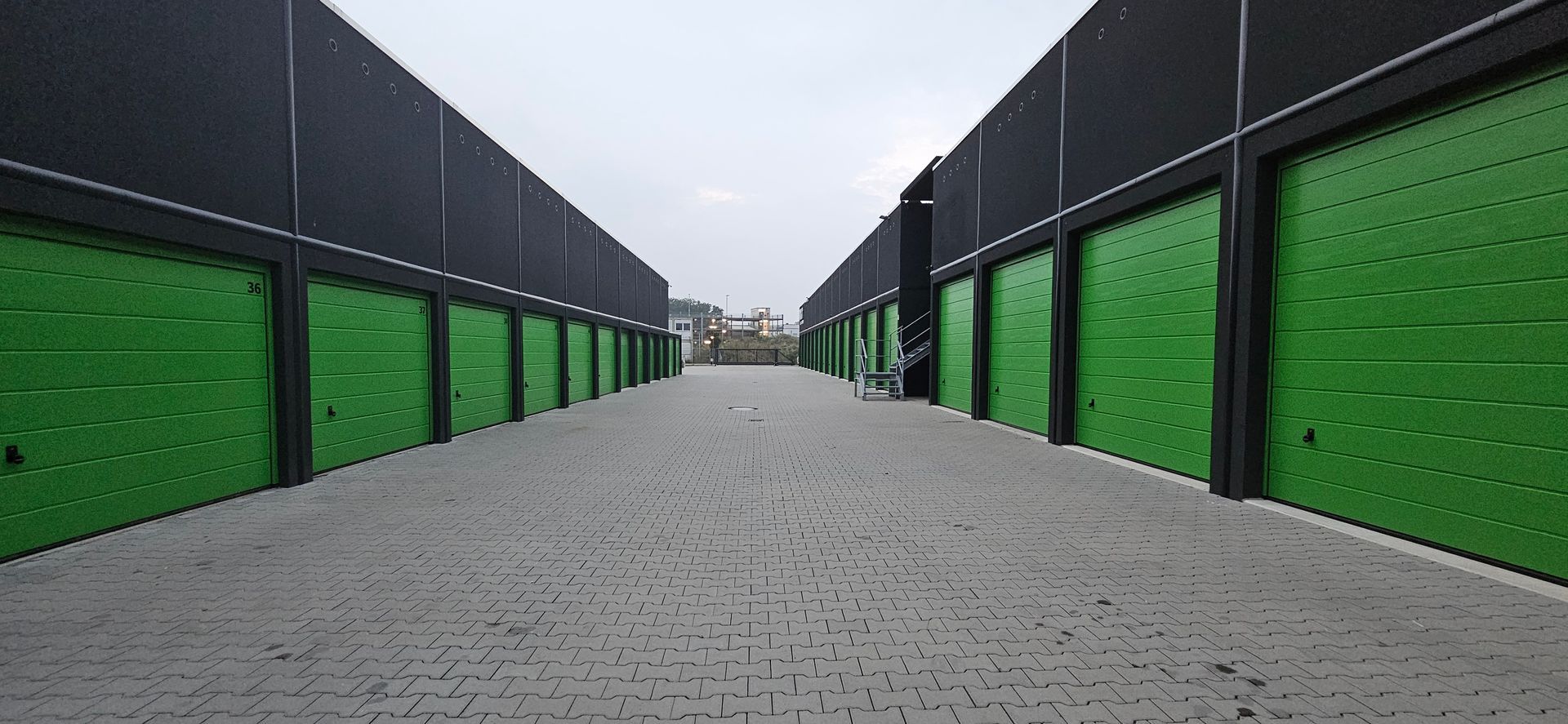 Auf einem Parkplatz steht eine Reihe grüner Garagentore.