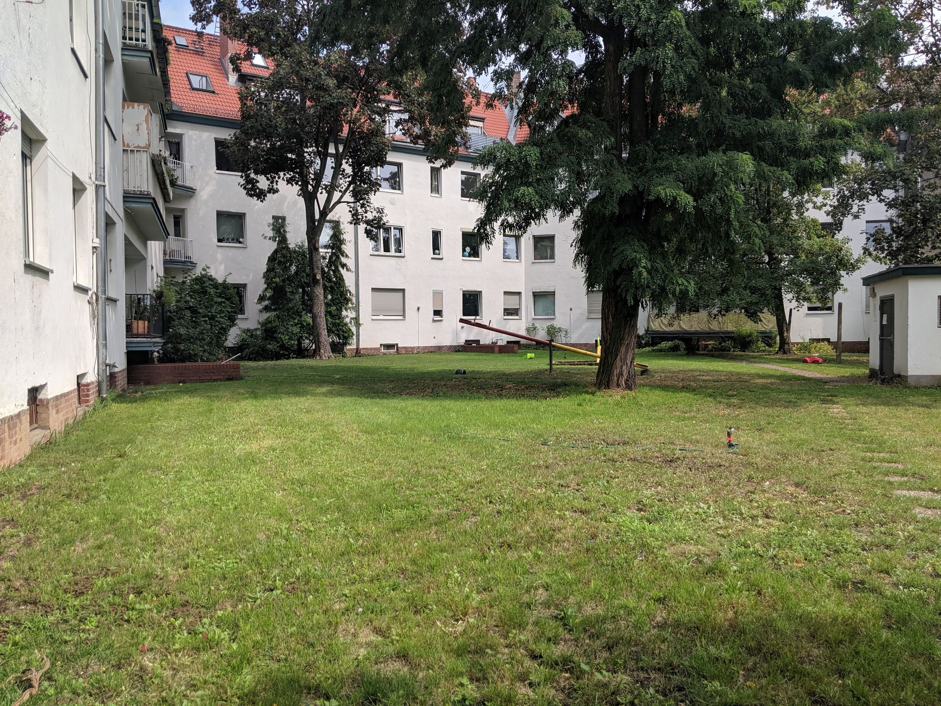 Eine große Wiese vor einem Gebäude mit Bäumen im Hintergrund.