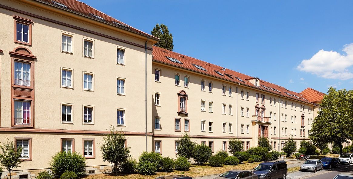 Ein großes Gebäude mit vielen Fenstern und davor geparkten Autos.